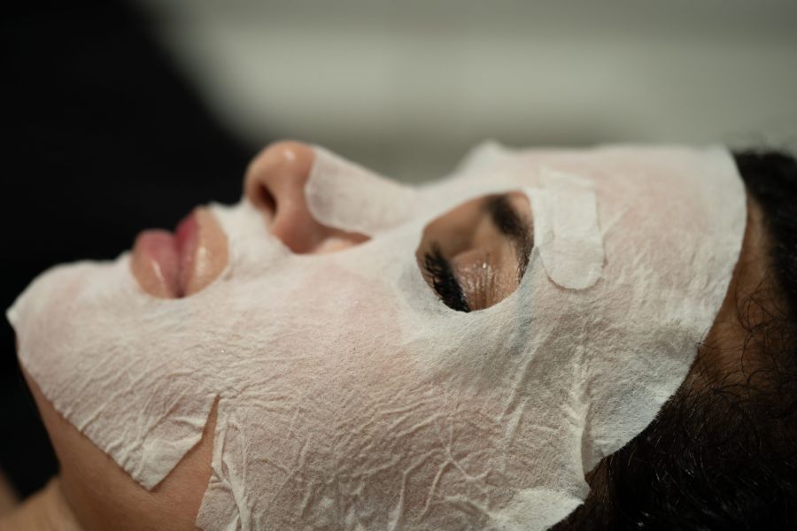 beautiful woman applying a paper facial mask