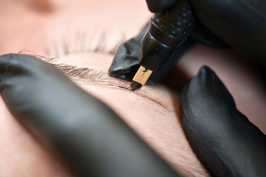 Microblading eyebrows, getting facial care and tattoo at beauty